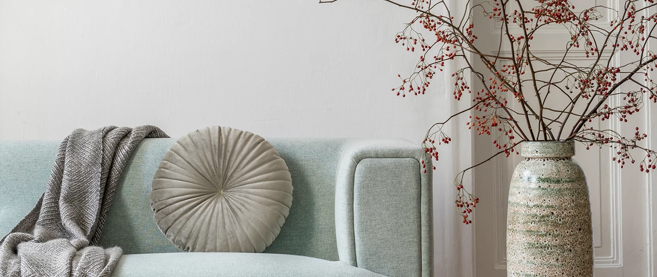 Détail d’un salon raffiné avec canapé pastel et vase décoratif en céramique à Montréal